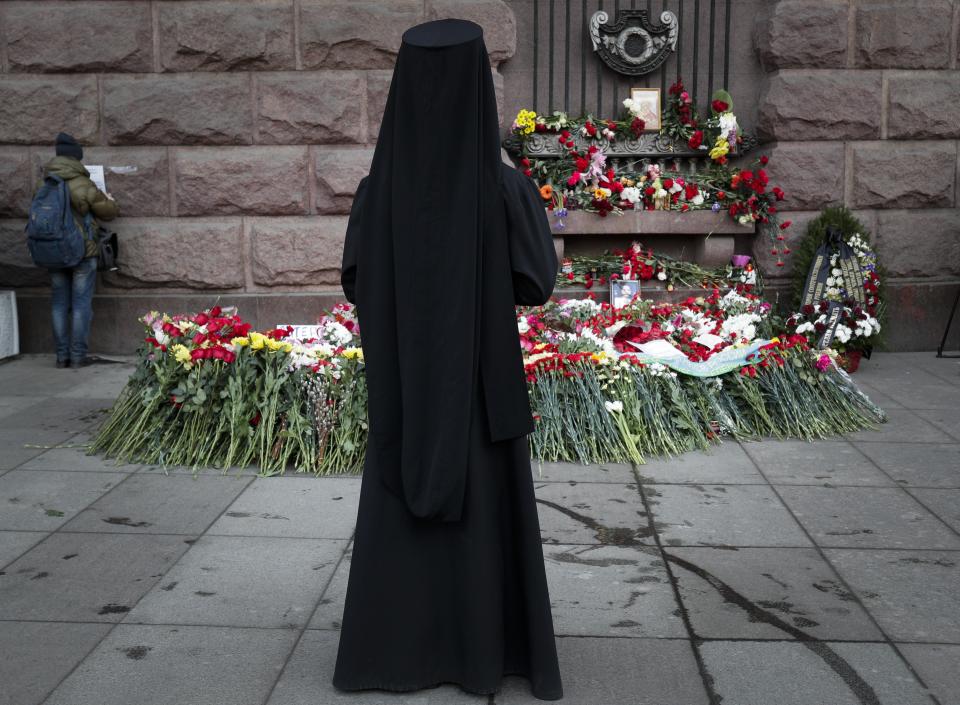 An Orthodox priest stands at a symbolic floral memorial at Technologicheskiy Institute subway station in St. Petersburg, Russia, Tuesday, April 4, 2017. A bomb blast tore through a subway train deep under Russia's second-largest city St. Petersburg Monday, killing several people and wounding many more in a chaotic scene that left victims sprawled on a smoky platform. (AP Photo/Dmitri Lovetsky)