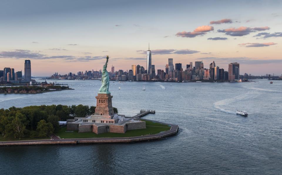 Aerial view of New York City with Statue of Liberty at sunset. (Getty Images)