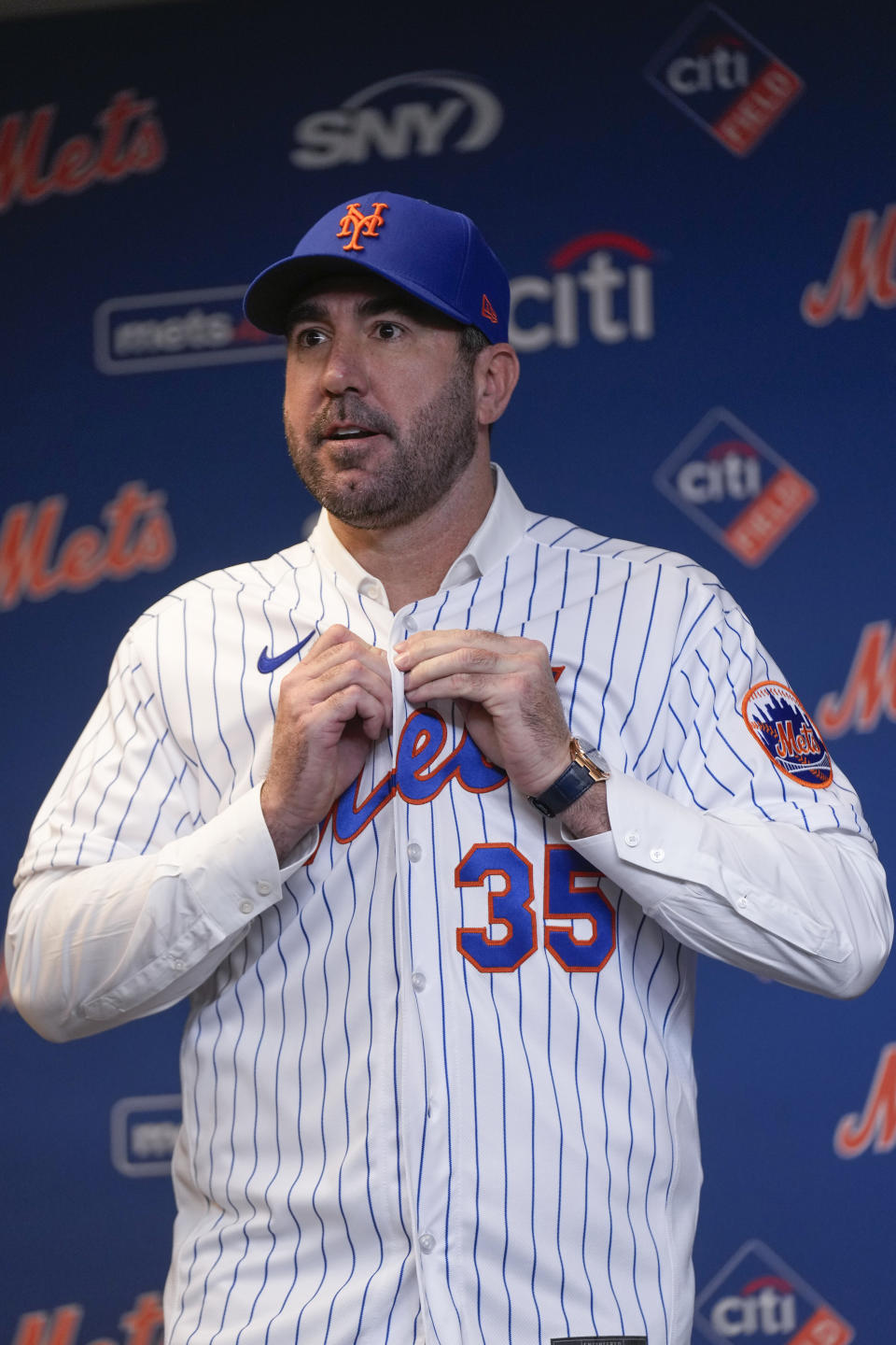 New York Mets baseball pitcher Justin Verlander puts on his new jersey during a news conference at Citi Field, Tuesday, Dec. 20, 2022, in New York. The team introduced Verlander after they agreed to a $86.7 million, two-year contract. It's part of an offseason spending spree in which the Mets have committed $476.7 million on seven free agents. (AP Photo/Seth Wenig)