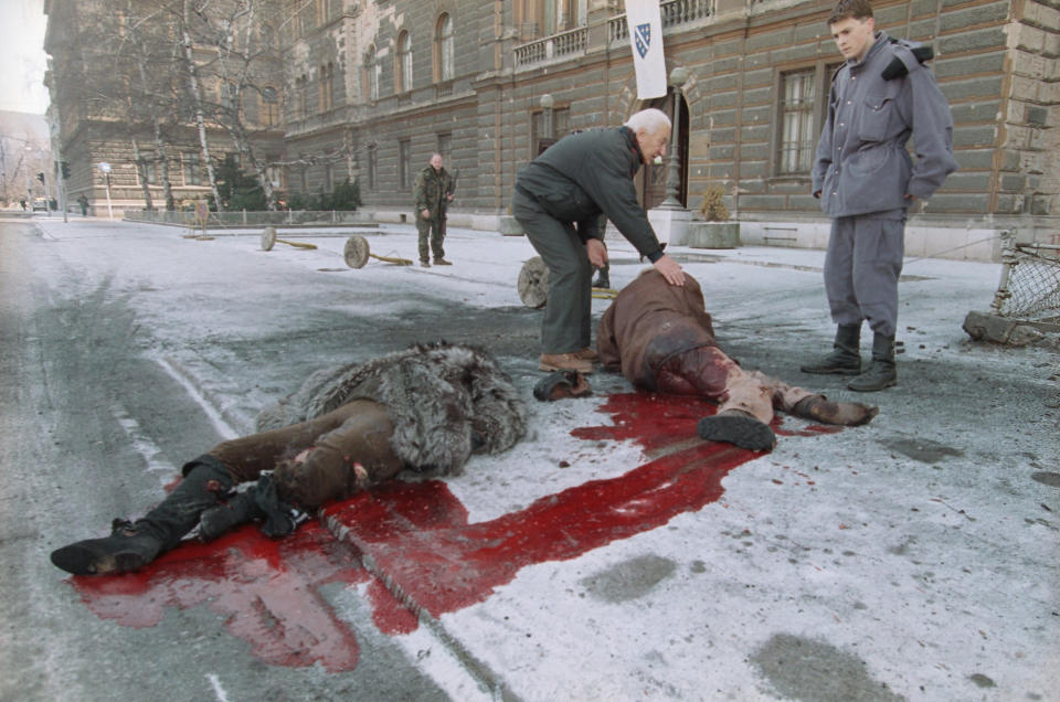 FILE - In this Jan. 30, 1993 file photo, Bosnian soldiers help injured people laying on the street in front of the Bosnian presidency after a shell hit the crowded street in Sarajevo. Western countries are reeling from the coronavirus pandemic, awakening to a new reality of economic collapse, overwhelmed hospitals and home confinement. But for millions across the Middle East and in conflict zones elsewhere, much of this is familiar. (AP Photo/Hansi Krauss, File)