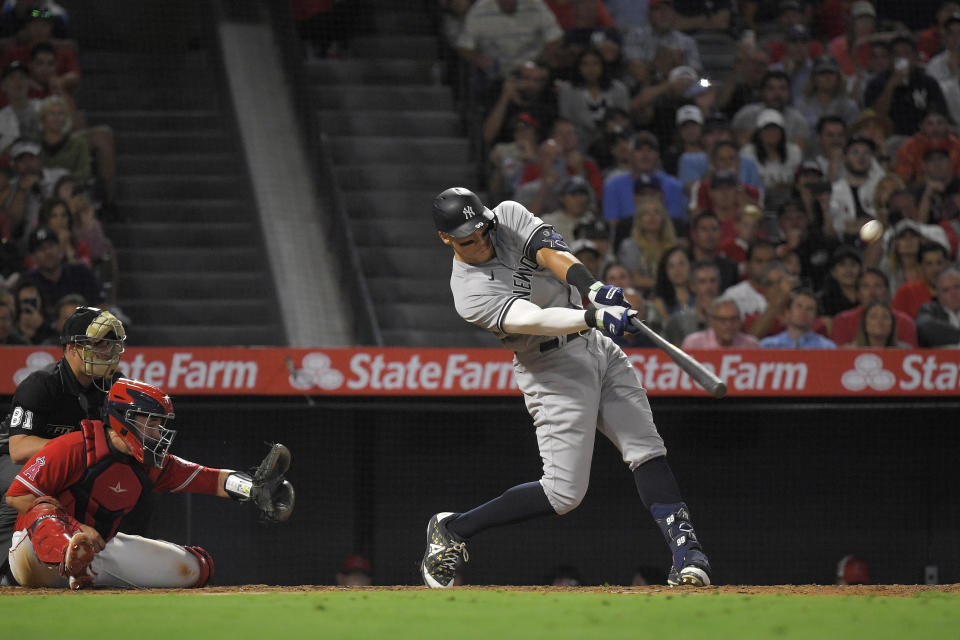 New York Yankees' Aaron Judge, right, hits a solo home run as Los Angeles Angels catcher Matt Thaiss, center, and home plate umpire Quinn Wolcott watch during the eighth inning of a baseball game Monday, Aug. 29, 2022, in Anaheim, Calif. This was Judge's 50th home run of the season. (AP Photo/Mark J. Terrill)