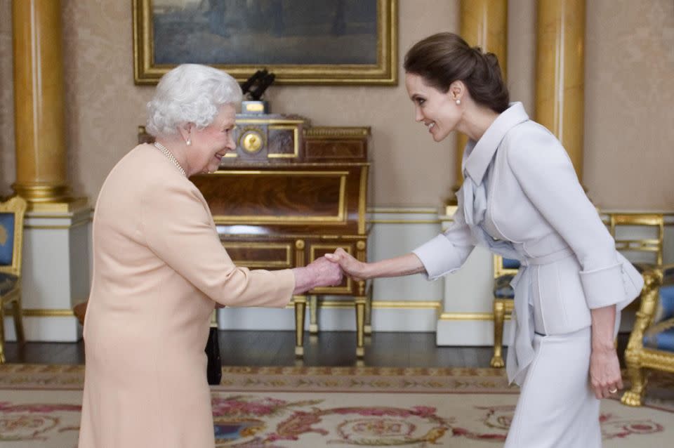 Angelina Jolie is presented with the Insignia of an Honorary Dame Grand Cross of the Most Distinguished Order of St Michael and St George by Britain's Queen Elizabeth on October 10, 2014. Source: Getty.