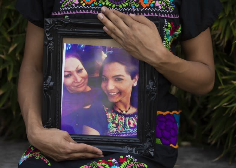 RESEDA, CA - AUGUST 18: Portrait of Pink Moon Midnight Blue holding a photo of her friend Angela Martinez, left, on Tuesday, Aug. 18, 2020 in Reseda, CA. Pink Moon Midnight Blue, was a close friend of Angela Martinez, who died recently of COVID. Martinez identified herself as "muxe," third gender recognized by the Zapotec indigenous community in Mexico. Midnight Blue is transgender and said Martinez pointedly said she was neither man, nor woman, nor trans, but muxe. Midnight Blue is wearing a dress given to her by Martinez. She said Martinez was like a mother to her. (Francine Orr / Los Angeles Times)