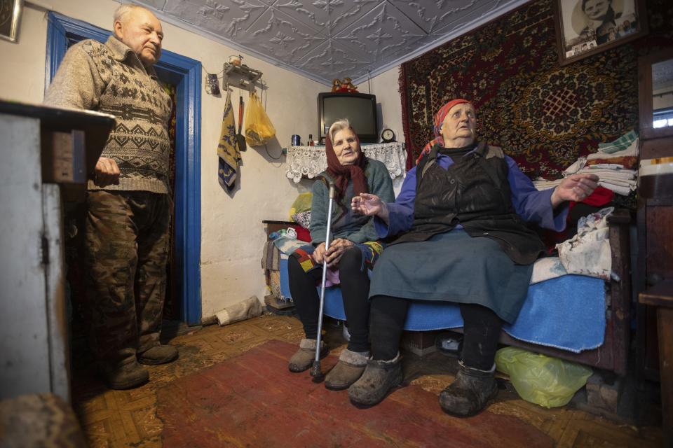 Kateryna Shklyar, right, speaks to The Associated Press as her husband, Dmytro, left, and Halyna Moroka gather near her at her house in the village of Nevelske in eastern Ukraine, on Friday, Dec. 10, 2021. With the bloody conflict between Russia-backed separatists and Ukrainian forces now more than seven years old, there are fears that a buildup of armed forces on Russia's side of the border could lead to an invasion or the resumption of full-scale hostilities. “We don't want war!" exclaimed Kateryna Shklyar, who shares the fear with her husband. (AP Photo/Andriy Dubchak)