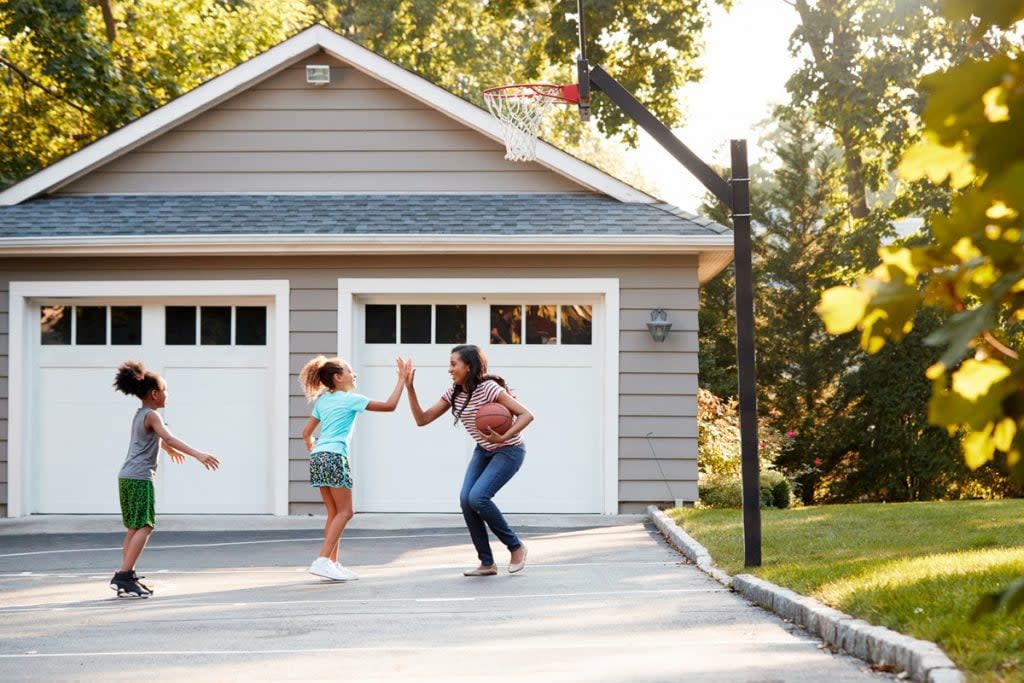 A mother high fives one of her daughters as she plays basketball outside of her house with two of her daughters. 