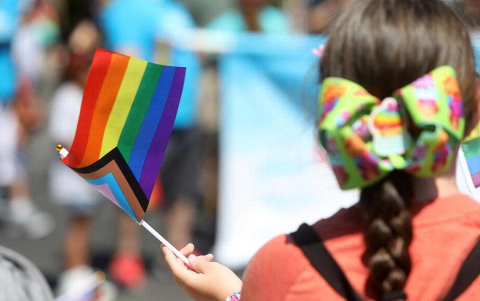 A girl waves a pride flag while watching the Fresno Rainbow Pride Parade in the Tower District on June 3, 2023.