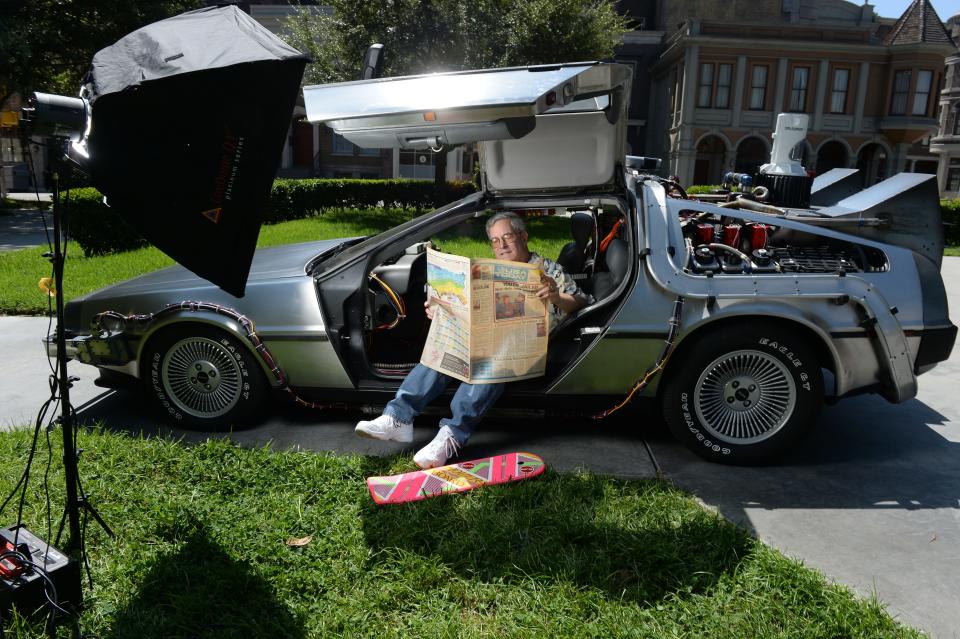 Bob Gale, co-writer and co-producer of the "Back to the Future movies," looks over a copy of USA TODAY while sitting in a restored DeLorean time machine owned by screenwriter Terry Matalas in Courthouse Square at Universal Studios, Los Angeles, in 2015.