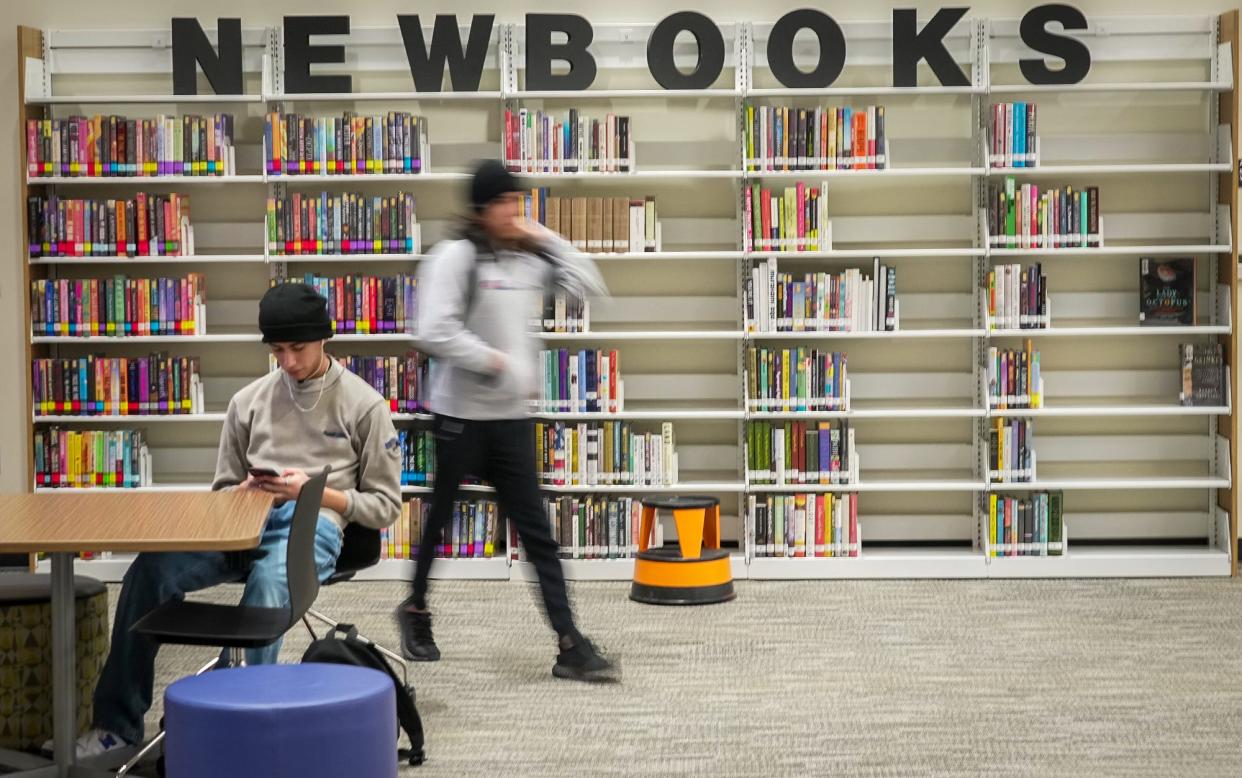 Nick Herrera looks at his phone while taking a break in the Lake Travis High School Library in January, The Lake Travis school board is to consider a parent's request to remove two books from the high school’s library.