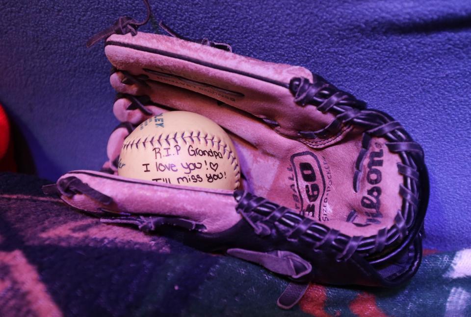 A glove and softball from a granddaughter rests in Jimmy Lehr's casket at the All Around Bar in Taylor, Mich. on Thursday, Feb. 13, 2014. The suburban Detroit bar fulfilled the wish of their longtime employee who asked that his funeral be held at the watering hole where he worked for about 25 years. The 58-year-old died Feb. 7 after having pulmonary disease and congestive heart failure. A pine casket built at the bar was surrounded by flowers on the dance floor during a Wednesday wake. It's the same floor where Lehr's fourth wedding was held in 1996. (AP Photo/Carlos Osorio)