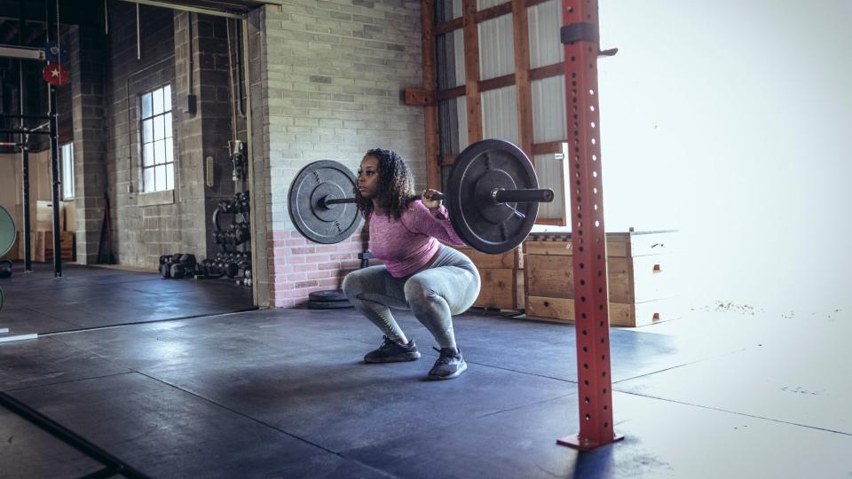 Woman squatting down with barbell