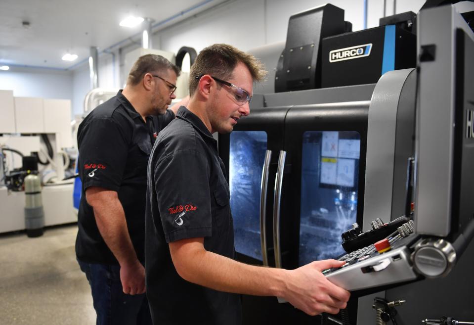 Brentyn Szalbirak, right, is a graduate of the tool and die apprentice program at PGT Innovations in Venice. He works at a CNC machine with team leader Seth Grigsby, left.