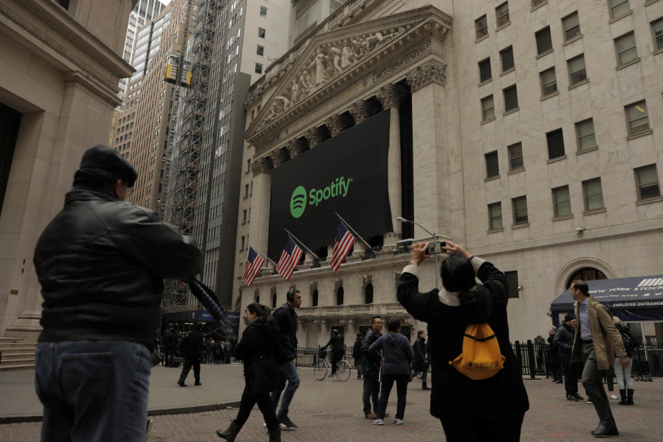 Pedestrians walk past a banner with the Spotify logo on it as the company lists its stock on the New York Stock Exchange with a direct listing in New York, U.S., April 3, 2018. REUTERS/Lucas Jackson