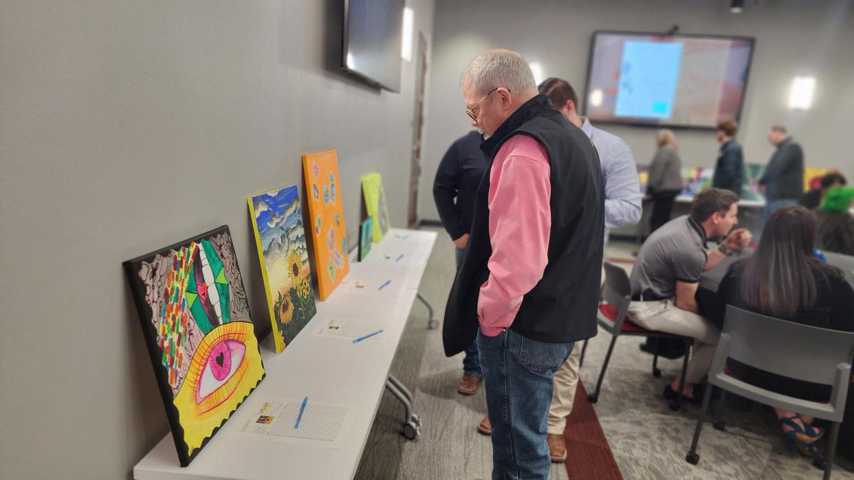 An attendee looks over one of the 30 pieces of art submitted to the silent auction at the 2023 HeART of CASA fundraiser in downtown Amarillo.