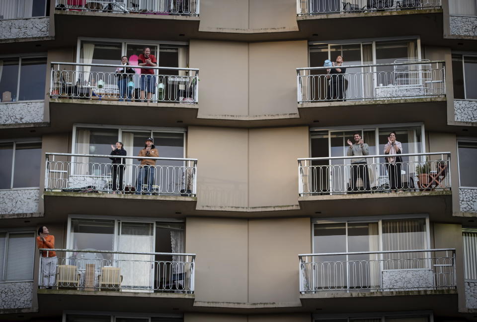People on apartment balconies applaud and make noise in a daily show of support for healthcare workers who are fight the coronavirus, in the West End of Vancouver, British Columbia, Tuesday, March 24, 2020. (Darryl Dyck/The Canadian Press via AP)