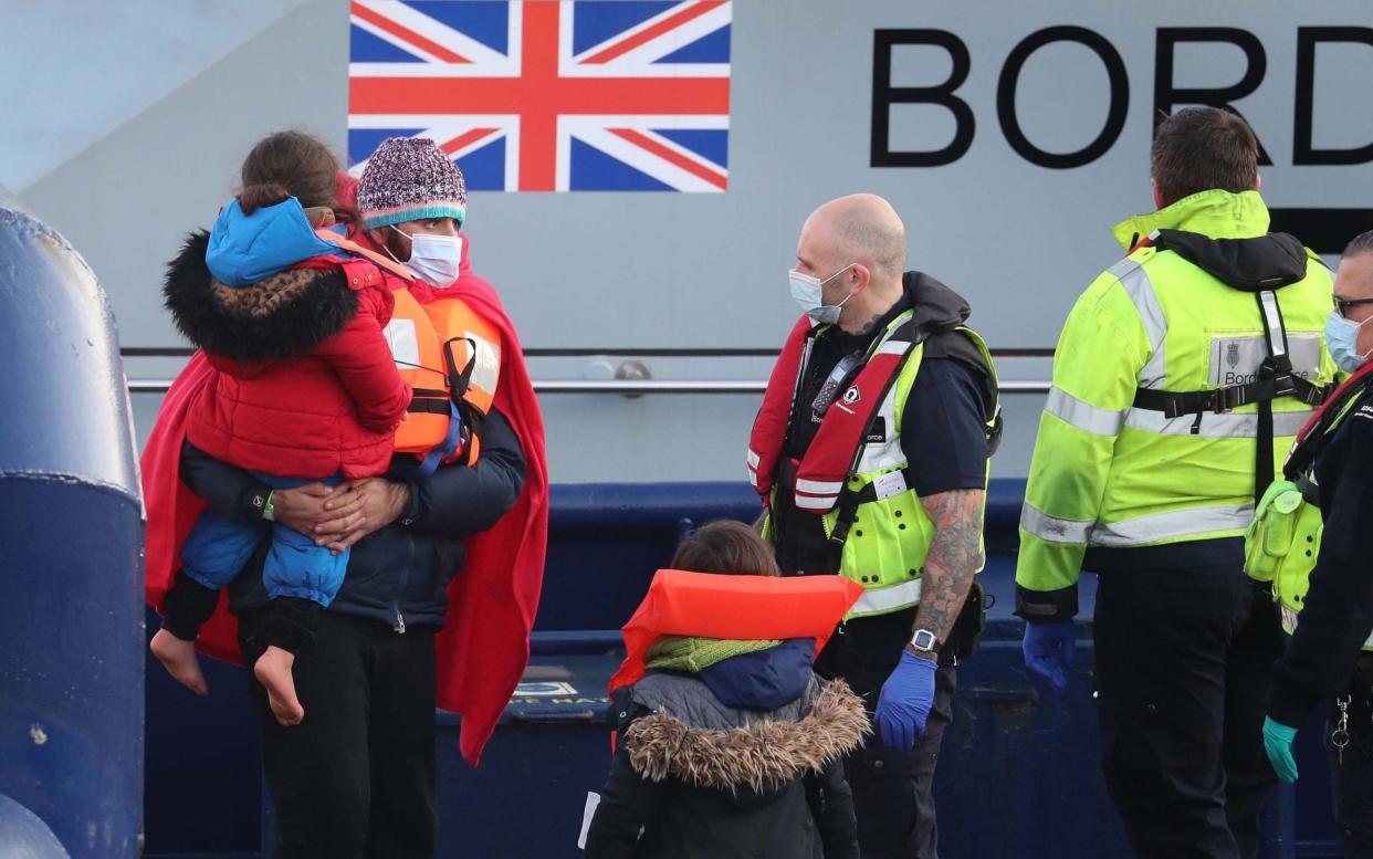 A man carries a young girl as a group of people thought to be migrants are brought in to Dover, Kent, by Border Force officers last month - Gareth Fuller/PA