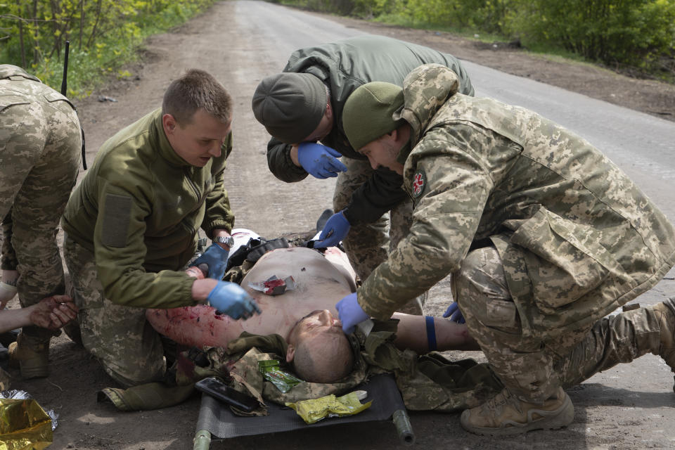 Military medics give first aid to wounded soldiers on the road near Bakhmut, Donetsk region, Ukraine, Thursday, May 11, 2023. (AP Photo/Boghdan Kutiepov)