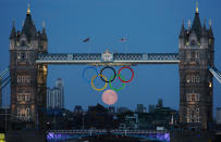 The full moon rises through the Olympic Rings hanging beneath Tower Bridge during the London 2012 Olympic Games August 3, 2012. REUTERS/Luke MacGregor (BRITAIN - Tags: SPORT OLYMPICS ENVIRONMENT CITYSPACE)