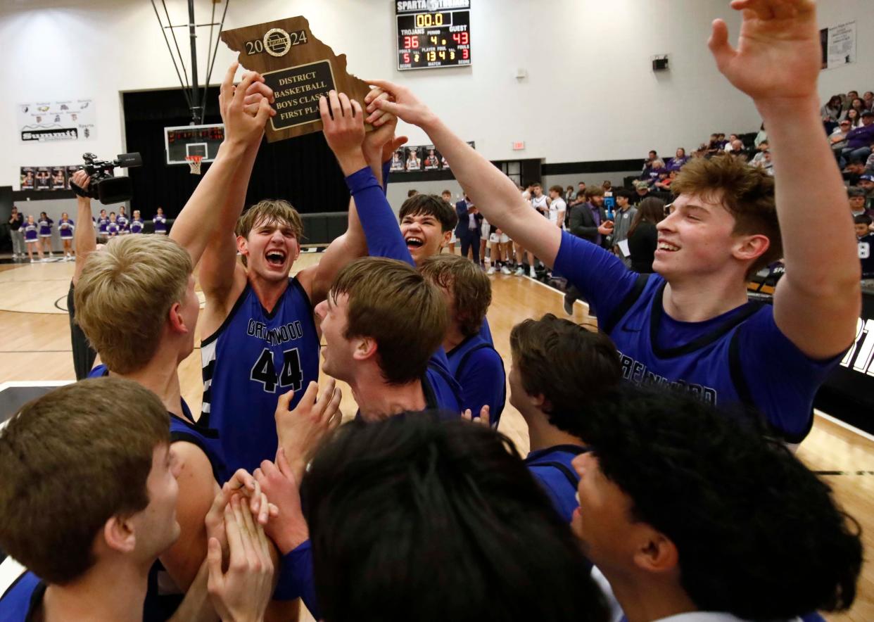 Greenwood's Garrett Winslow raises the district winners trophy after beating Fair Grove during the district tournament at Sparta High School on February 24, 2024.