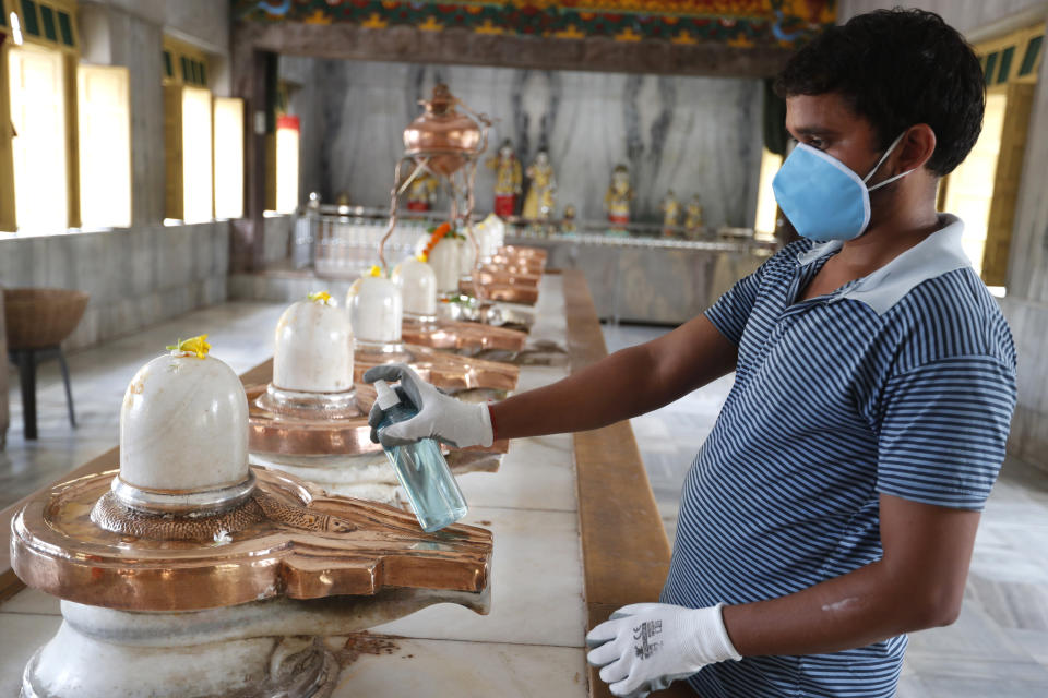 An employee of a temple sanitizes Shivlings in Prayagraj, India, Monday, June 8, 2020. Religious places, malls, hotels and restaurants open Monday after more than two months of lockdown as a precaution against coronavirus. (AP Photo/Rajesh Kumar Singh)