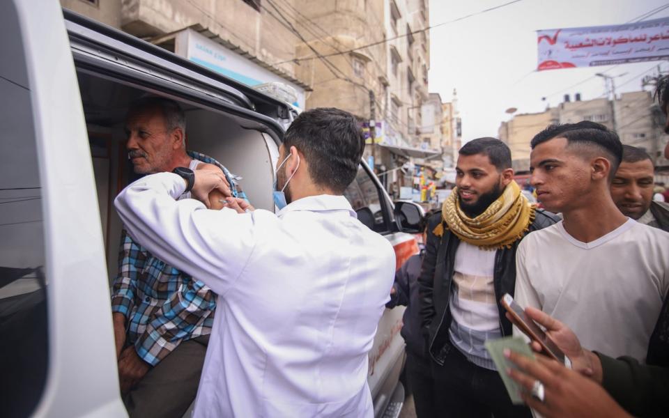 Health workers giving out Covid vaccines in Gaza on Tuesday - BLOOMBERG