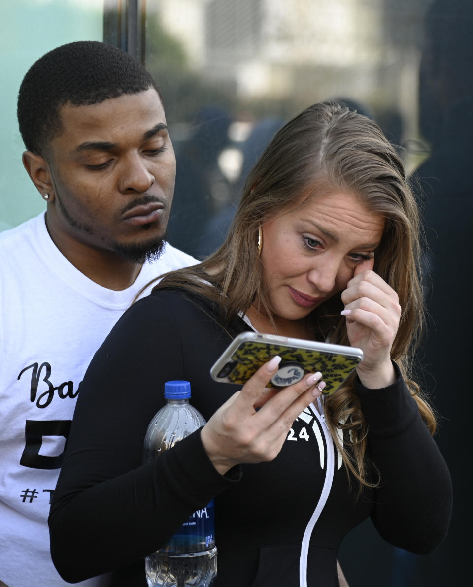 A women wipes tears while watching a public memorial for former Los Angeles Lakers star Kobe Bryant and his daughter, Gianna on a phone near the Staples Center, in Los Angeles, Monday, Feb. 24, 2020. (AP Photo/Kelvin Kuo)