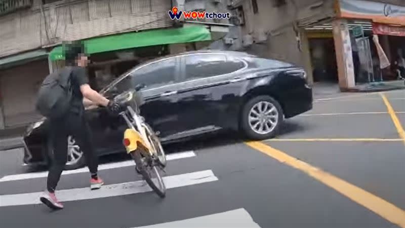 一名年輕男子牽YouBike過馬路時，手中的單車與轎車發生擦撞。（圖／翻攝自YouTube－WoWtchout - 地圖型行車影像分享平台頻道）