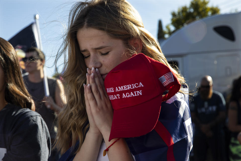 Liza Durasenko, 16, from Oregon City, Ore., prays during a rally in support of President Donald Trump on Saturday, Aug. 29, 2020, in Clackamas, Ore. (AP Photo/Paula Bronstein)