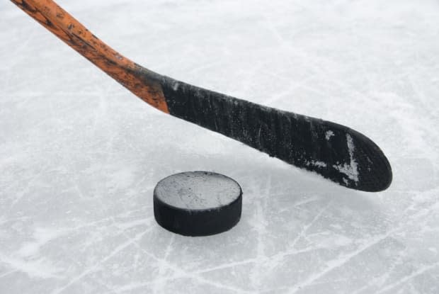 A hockey stick and puck are seen in this stock photo. There are concerns about the future of hockey at the Victoria Highland Civic Centre in Baddeck, N.S., after an engineer's report found a laundry list of issues, including a leaky roof and rusting beams.  (Shutterstock - image credit)