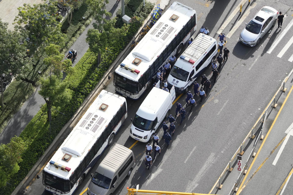 Chinese police and security personnel march past police vehicles outside the Evergrande headquarters in Shenzhen, China, Friday, Sept. 24, 2021. Fears that the Chinese real estate developer's possible default on multibillion-dollar debts might send shockwaves through global financial markets appeared to ease Thursday as creditors waited to see how much they might recover. (AP Photo/Ng Han Guan)