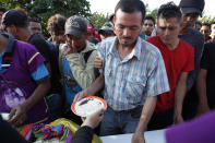 A Honduran migrant receives breakfast at a temporary shelter in Tecun Uman, Guatemala in the border with Mexico, Sunday, Jan. 19, 2020. Mexican authorities have closed a border entry point in southern Mexico after thousands of Central American migrants tried to push across a bridge between Mexico and Guatemala. (AP Photo/Moises Castillo)