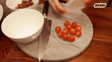 slicing through cherry tomatoes between two deli lids