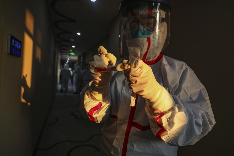 A medical worker in a protective suit writes on a tube after collecting a sample for nucleic acid tests from a suspected virus patient at a hotel being used to place people in medical isolation in Wuhan in central China's Hubei Province, Tuesday, Feb. 4, 2020. Hong Kong hospitals cut services as thousands of medical workers went on strike for a second day Tuesday to demand the border with mainland China be shut completely, as a new virus caused its first death in the semi-autonomous territory and authorities feared it was spreading locally. (Chinatopix via AP)