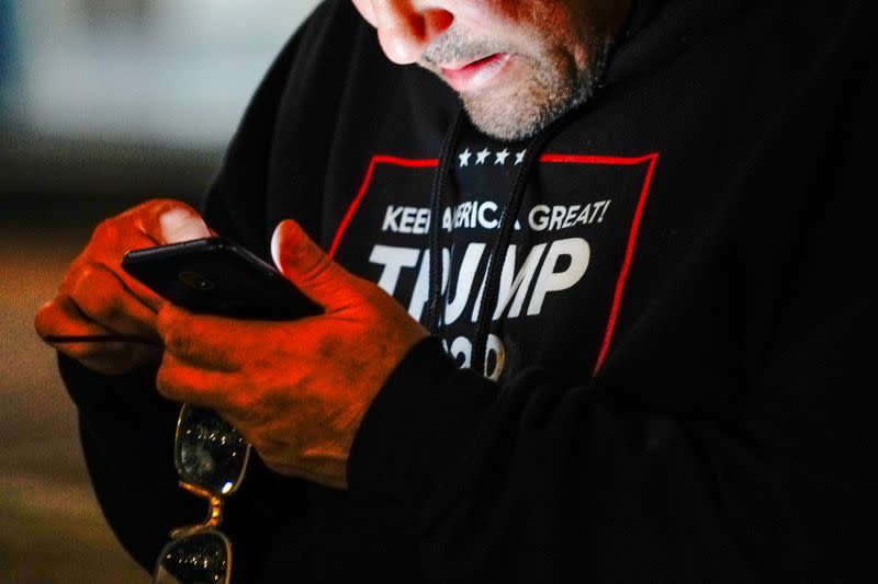 A man wearing a "Trump 2020" sweatshirt uses his mobile phone during a "Stop the Steal" protest outside Milwaukee Central Count the day after Milwaukee County finished counting absentee ballots, in Milwaukee