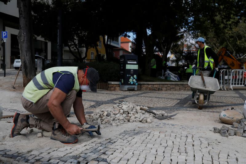 Dos hombres trabajan en una calle de Cascais mientras continúa la propagación del coronavirus