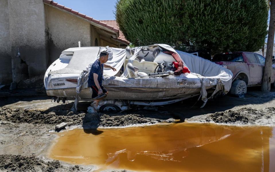 Ronald Mendiola next to a boat stuck under a tree on his front yard