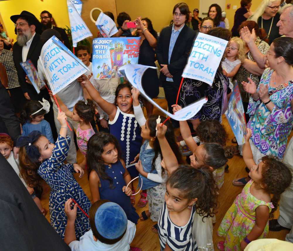 Children wave flags that say they are "Rejoicing With the Torah" when Chabad of Southside dedicated its new Torah scroll on Sept. 6, 2015. The dedication came on the cusp of the High Holidays, which includes Simchas Torah, a time for celebrating the Jewish holy book through song and dance.