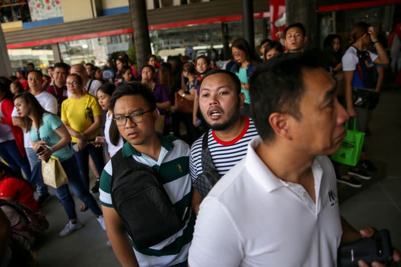 Shoppers and vendors stand outside Virra Mall where gunshots were fired in San Juan City, Metro Manila