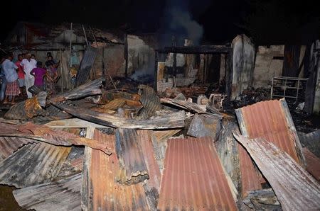 People stand next to burnt shops after gunmen flung grenades in a market on the outskirts of Kokrajhar town, in Assam, India, August 5, 2016. REUTERS/Stringer