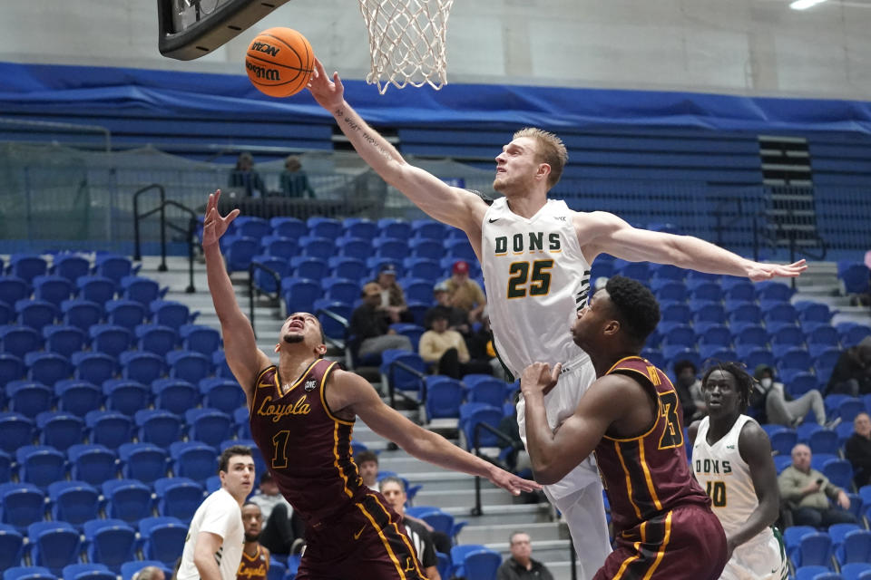 San Francisco forward Yauhen Massalski (25) blocks the shot of Loyola guard Lucas Williamson (1) in the first half during an NCAA college basket ball game Thursday, Jan. 6, 2022, in Taylorsville, Utah. Struggling to find opponents amid the coronavirus chaos, San Francisco and Loyola Chicago decided to meet in the middle. (AP Photo/Rick Bowmer)