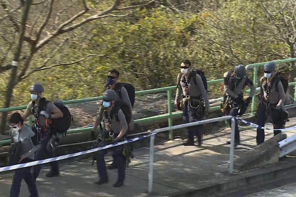 In this image taken from video footage provided by TVB Hong Kong, police officers prepare to conduct a search on a hillside following a murder case of a model, in Hong Kong on Sunday, Feb. 26, 2023. Police in Hong Kong have filed murder charges against the former in-laws of a model, days after her body parts were found in a refrigerator. A police statement says Hong Kong model Abby Choi’s father-in-law and his eldest son are being charged with murder, while her mother-in-law faces one count of perverting the course of justice. (TVB Hong Kong via AP)