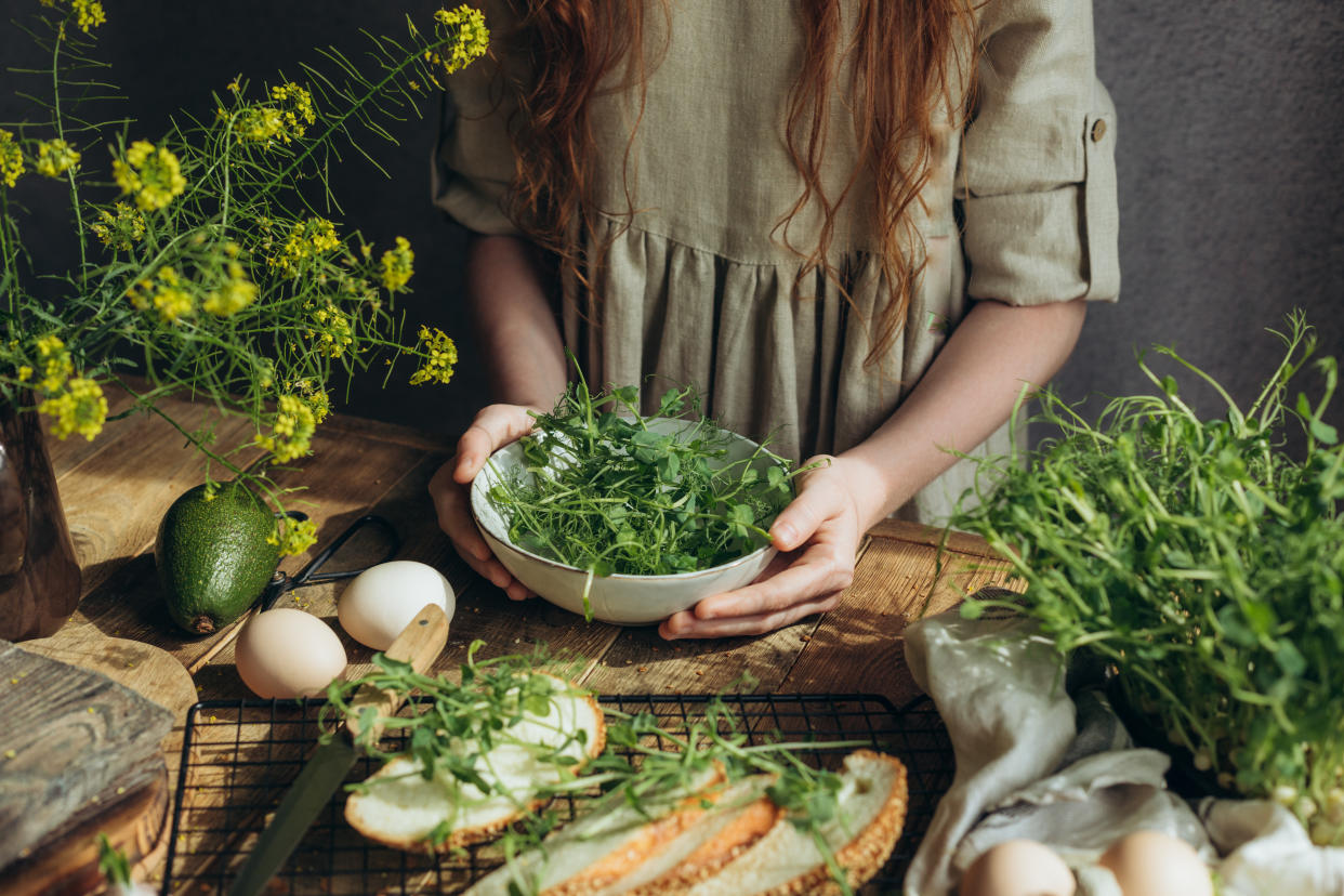 Sorting sprouts of greens on a wooden breakfast table.