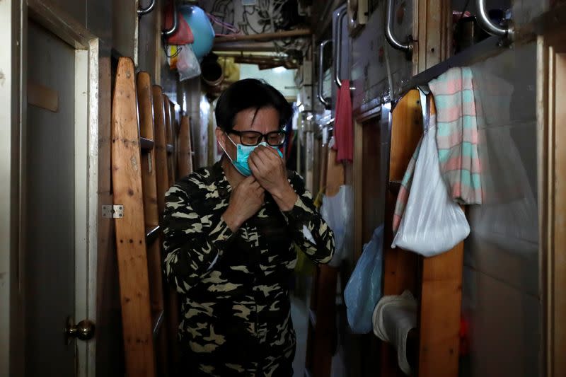 Simon Wong, 64, adjusts a protective mask outside his 2 square metre subdivided residential unit, known as a "coffin home", following the outbreak of the new coronavirus, in Hong Kong