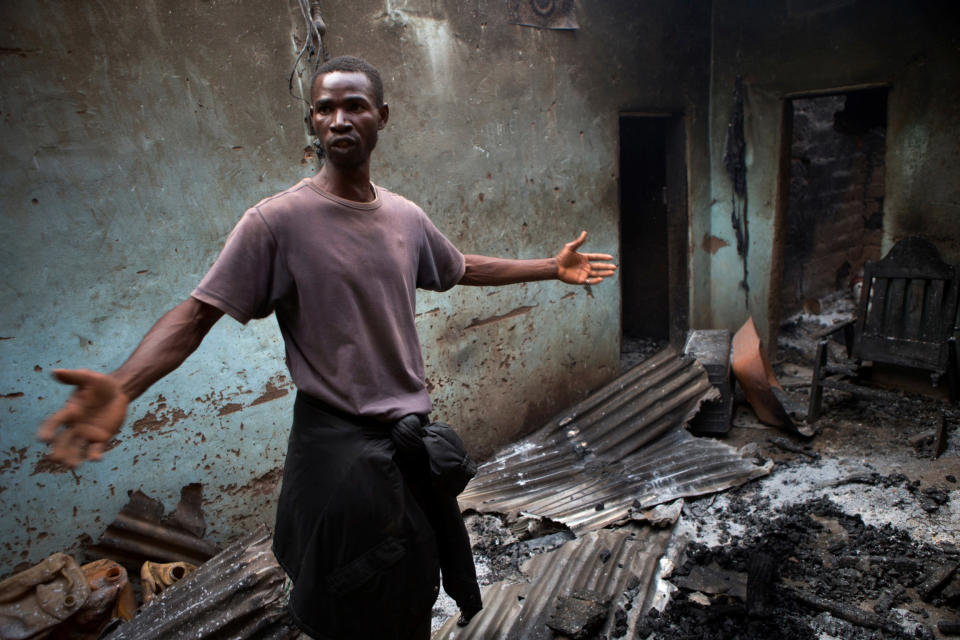 A neighborhood resident returning from a makeshift camp for the displaced at Mpoko Airport to fetch household goods surveys the remains of a burned home said to belong to a Christian family, in Bangui, Central African Republic, on New Year's Day, Wednesday, Jan. 1, 2014. Clashes between armed gangs of Muslim and Christian residents continued in the 5th Arrondissement area on Wednesday, with neighborhood residents reporting at least four people killed. In Garaba, several homes belonging to Christians were burned, and multiple Muslim homes looted. (AP Photo/Rebecca Blackwell)