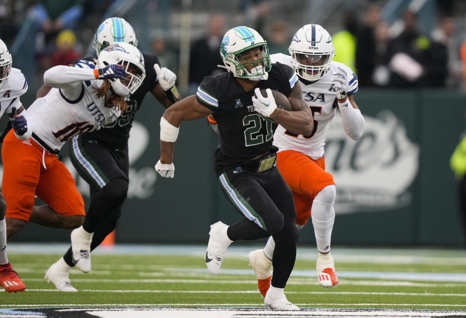Tulane running back Makhi Hughes (21) carries past UTSA linebackers Martavius French (10) and Avery Morris on a 58-yard run in the first half of an NCAA college football game in New Orleans, Friday, Nov. 24, 2023. (AP Photo/Gerald Herbert)