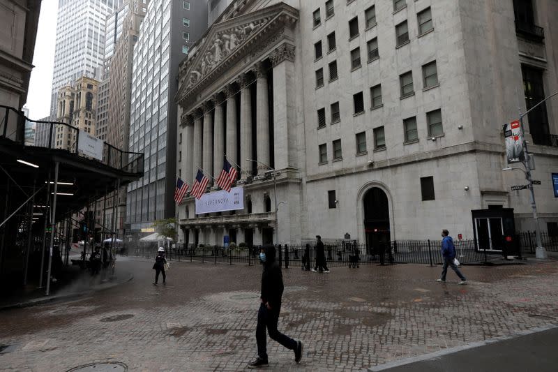 People wearing protective face masks walk outside New York Stock Exchange in New York