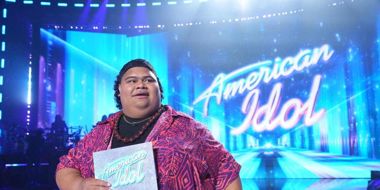 iam tongi looking off camera as he holds the winner envelope on the american idol stage