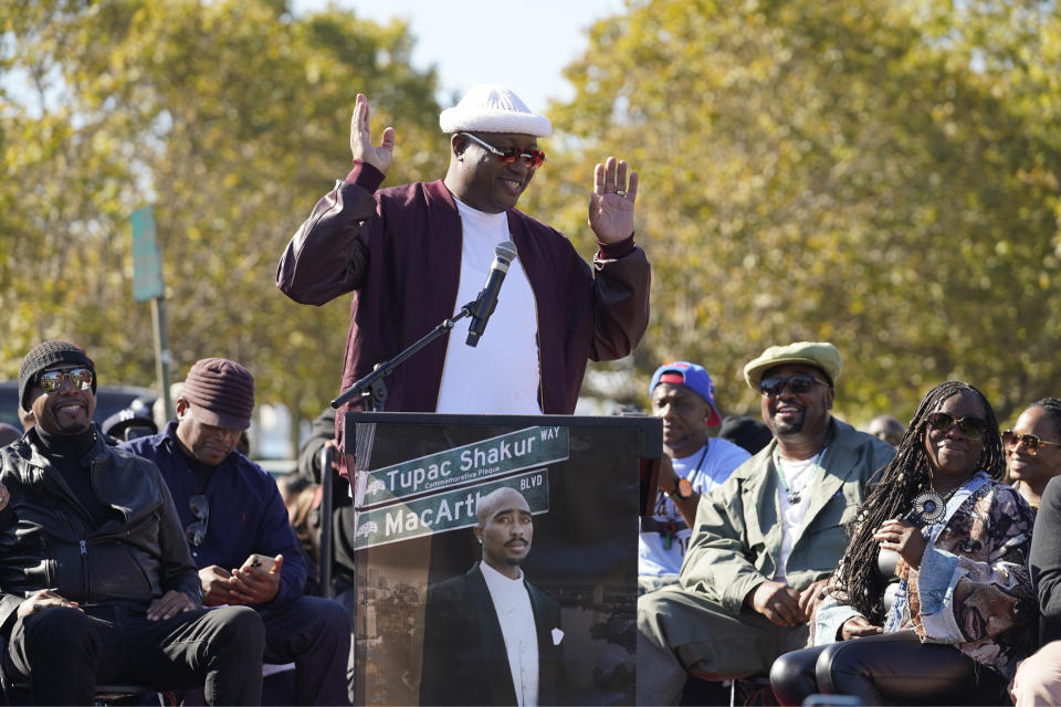 E-40 speaks during a street renaming ceremony for Tupac Shakur in Oakland, Calif., Friday, Nov. 3, 2023. A stretch of street in Oakland was renamed for Shakur, 27 years after the killing of the hip-hop luminary. Listening at left is MC Hammer, at right is Shakur's sister Sekyiwa Shakur and second from right is Fred Hampton Jr. (AP Photo/Eric Risberg)