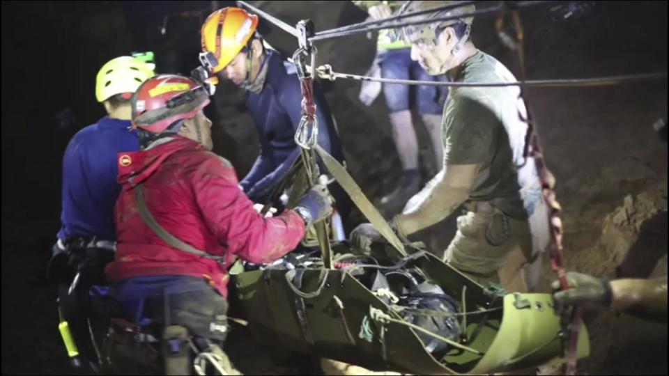 Rescuers hold one of the boys as they are stretched out of the cave (AP)