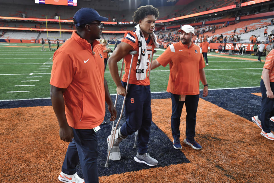 Syracuse tight end Oronde Gadsden II, center, walks off the field with crutches and a boot after an NCAA college football game against Western Michigan in Syracuse, N.Y., Saturday, Sept. 9, 2023. (AP Photo/Adrian Kraus)