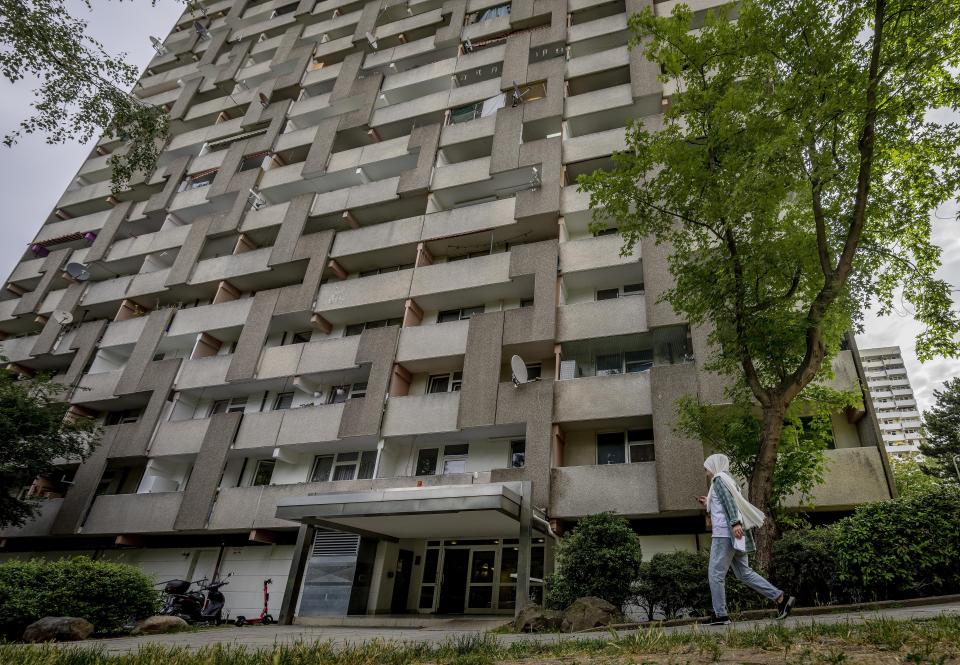 A young woman passes a resident building in the Frankfurter Berg district in Frankfurt, Germany, Wednesday, July 13, 2022. (AP Photo/Michael Probst)